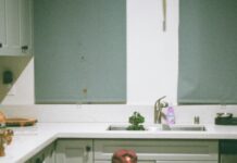 The Ultimate Puppy Training Schedule (8–16 Weeks Guide) Young man sitting on kitchen floor, gently holding a happy puppy in natural morning light.