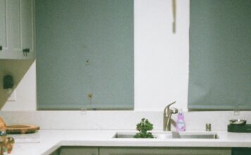 The Ultimate Puppy Training Schedule (8–16 Weeks Guide) Young man sitting on kitchen floor, gently holding a happy puppy in natural morning light.